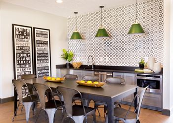 a kitchen with a table and chairs in front of a wall with green pendant lights at The Timbers Apartments, Evansville, 47715